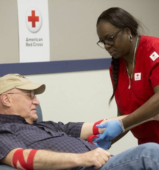 Red Cross nurse tying patients arm