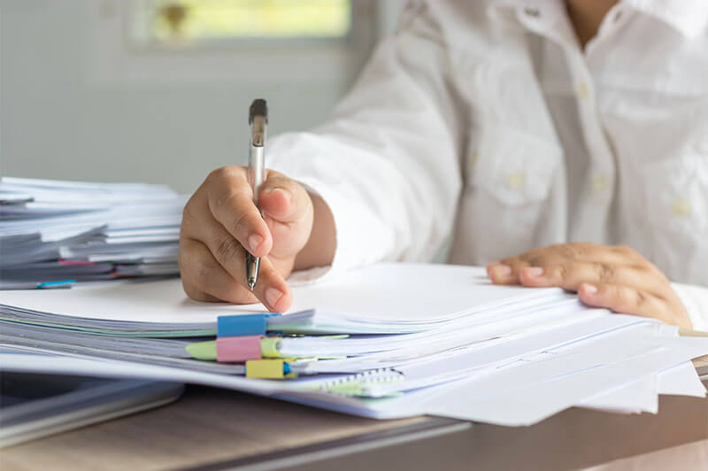 Person with pen in hand working on paperwork.